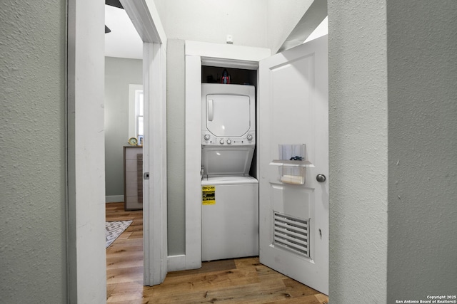 laundry area with stacked washer / drying machine and hardwood / wood-style floors