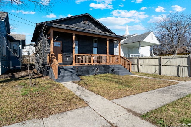 bungalow featuring covered porch and a front yard