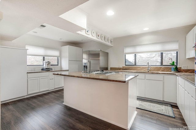 kitchen featuring stainless steel appliances, an island with sink, sink, and white cabinets