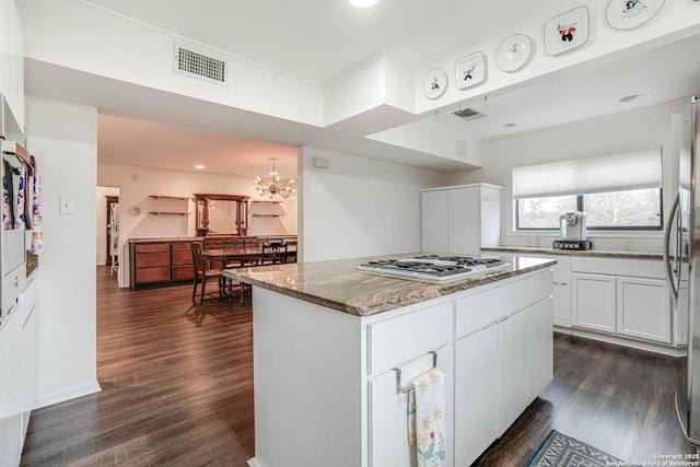 kitchen featuring white cabinetry, dark hardwood / wood-style flooring, a kitchen island, stone counters, and stainless steel appliances