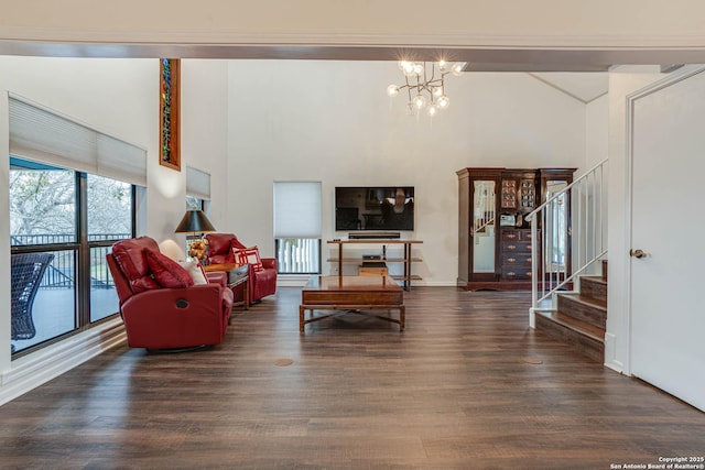 living room featuring a notable chandelier, a towering ceiling, and dark wood-type flooring