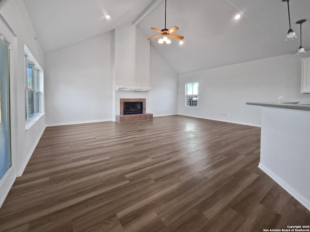 unfurnished living room with high vaulted ceiling, dark hardwood / wood-style flooring, beamed ceiling, ceiling fan, and a fireplace