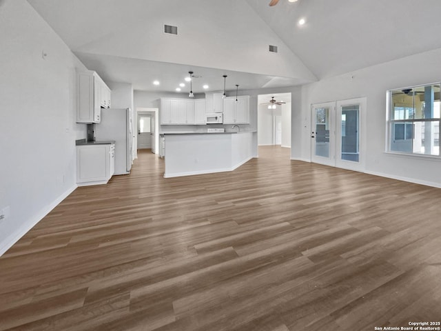 unfurnished living room with dark wood-type flooring, high vaulted ceiling, and ceiling fan