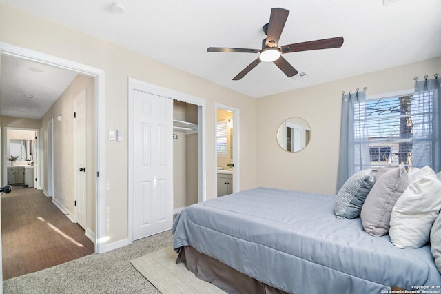 carpeted bedroom featuring ceiling fan, ensuite bathroom, and a closet