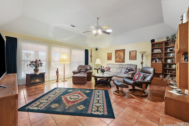 living room featuring a fireplace, tile patterned floors, a raised ceiling, and ceiling fan