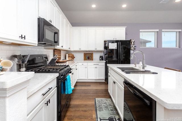 kitchen with sink, a kitchen island with sink, black appliances, white cabinets, and dark hardwood / wood-style flooring