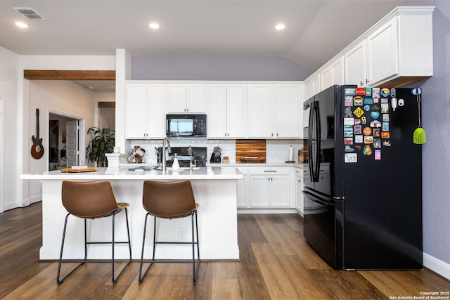 kitchen featuring white cabinetry, backsplash, black appliances, and an island with sink