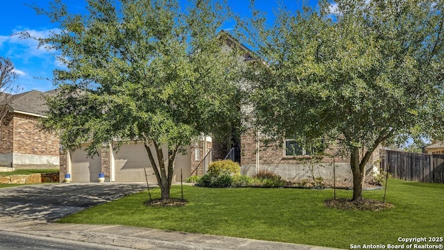 view of property hidden behind natural elements with brick siding, driveway, a front lawn, and fence