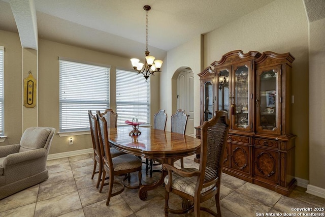 dining room featuring arched walkways, baseboards, and an inviting chandelier