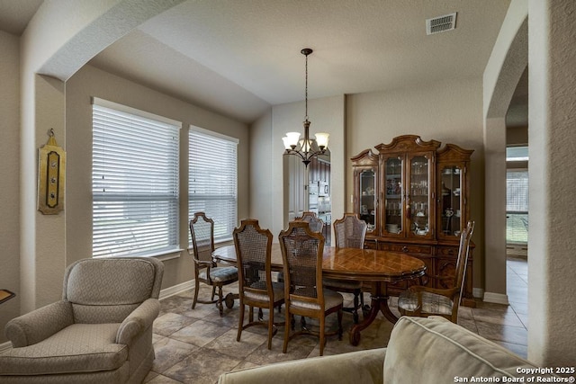 dining area featuring arched walkways, baseboards, visible vents, and a notable chandelier