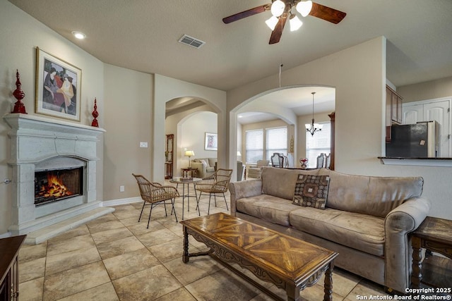 living room featuring light tile patterned flooring and ceiling fan with notable chandelier