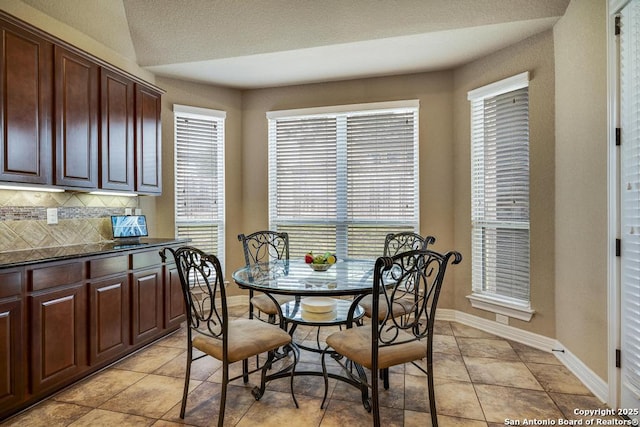 dining space with a healthy amount of sunlight, light tile patterned floors, and baseboards