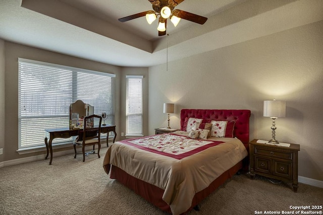 carpeted bedroom with a raised ceiling and ceiling fan