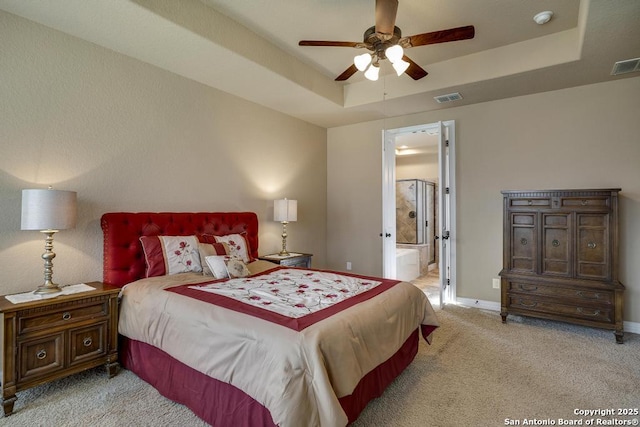 bedroom featuring ceiling fan, ensuite bathroom, a raised ceiling, and light carpet