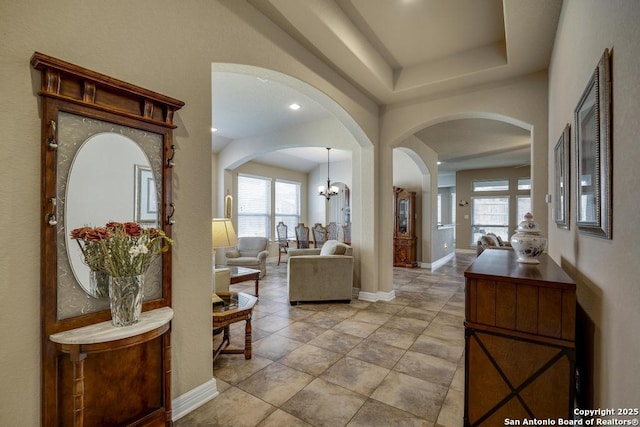 hallway with baseboards and an inviting chandelier