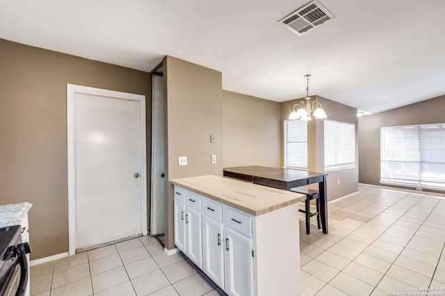 kitchen featuring light tile patterned floors, stainless steel stove, an inviting chandelier, hanging light fixtures, and white cabinets