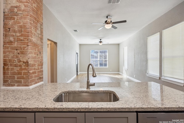 kitchen featuring dishwasher, sink, light stone counters, and light hardwood / wood-style flooring