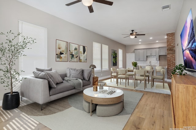 living room with wood-type flooring, sink, and ceiling fan