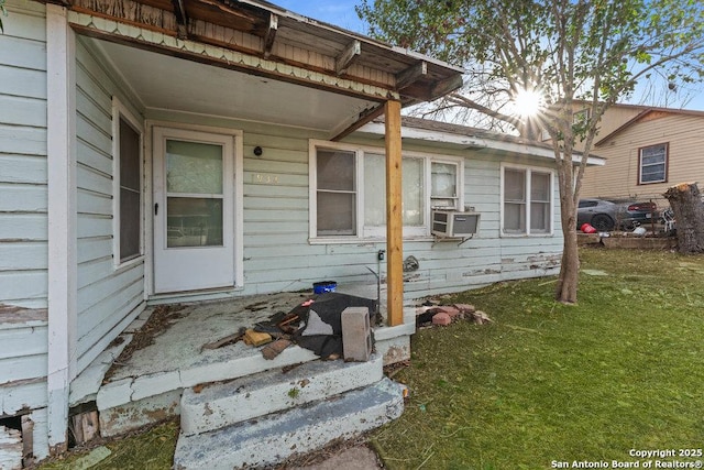 doorway to property with cooling unit and a lawn