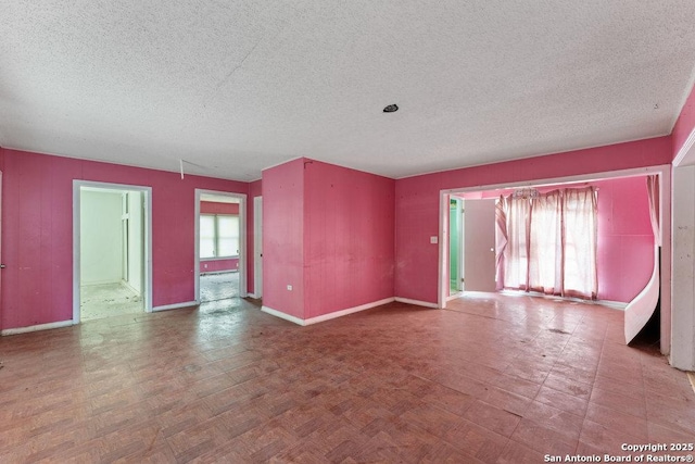 empty room featuring parquet flooring, a textured ceiling, and a wealth of natural light