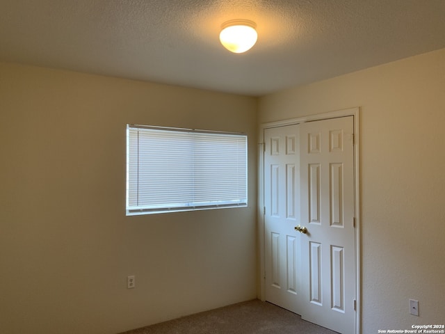 unfurnished bedroom with a closet, a textured ceiling, and carpet flooring