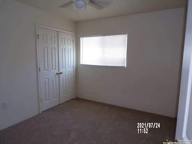 unfurnished bedroom with ceiling fan, carpet flooring, and a closet