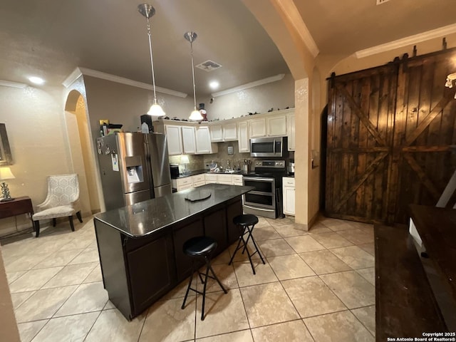 kitchen with a kitchen bar, white cabinetry, decorative light fixtures, a kitchen island, and stainless steel appliances