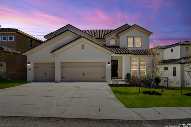 mediterranean / spanish house featuring a garage and a lawn