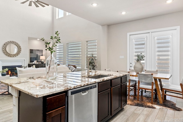 kitchen with dishwasher, dark brown cabinets, sink, and a kitchen island with sink