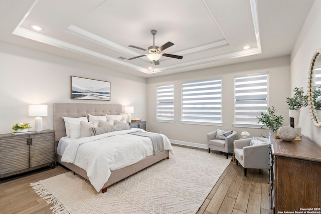 bedroom featuring light hardwood / wood-style floors, a raised ceiling, and ceiling fan