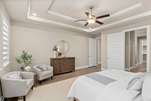 bedroom featuring ornamental molding, wood-type flooring, and a tray ceiling