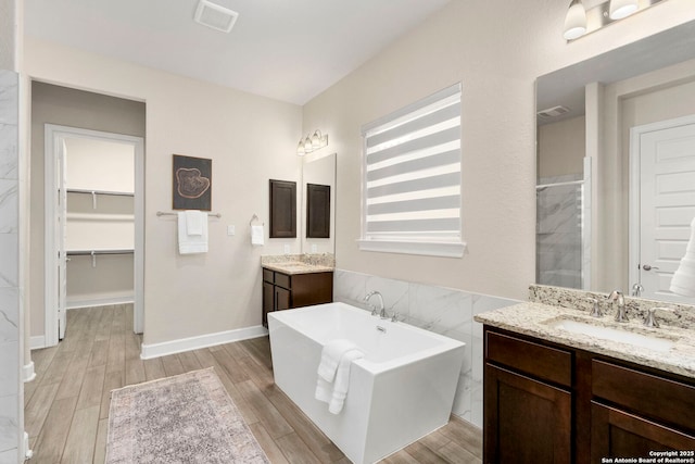 bathroom featuring wood-type flooring, separate shower and tub, vanity, and tile walls