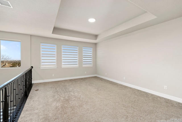 carpeted empty room featuring a raised ceiling