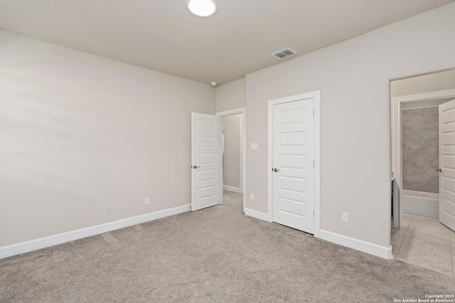 unfurnished bedroom with ensuite bath and light colored carpet