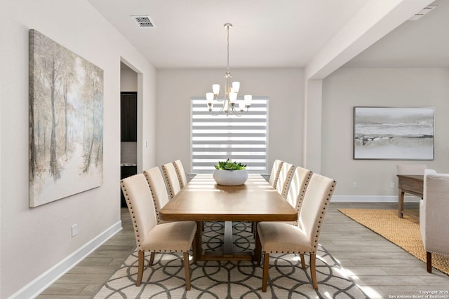 dining space with light hardwood / wood-style flooring and a chandelier