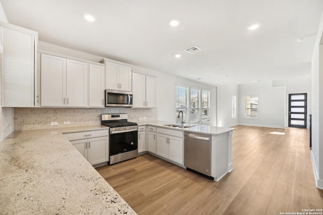 kitchen featuring sink, white cabinetry, stainless steel appliances, light stone countertops, and decorative backsplash