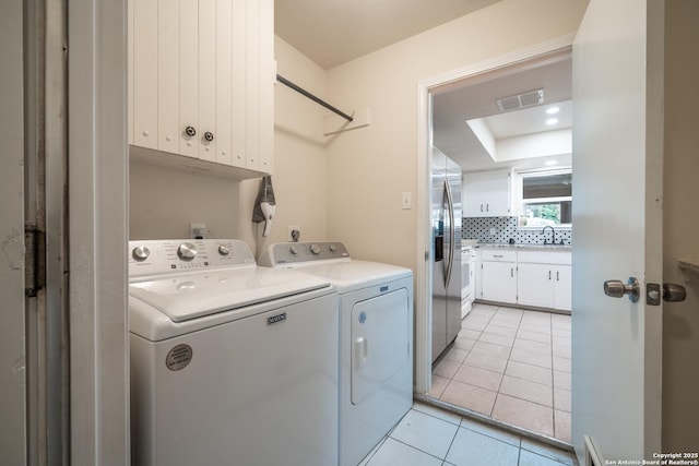 laundry area with cabinets, separate washer and dryer, sink, and light tile patterned floors