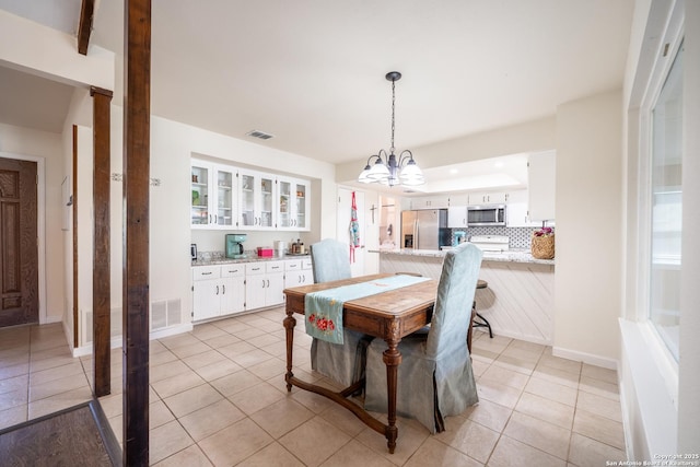 dining area with light tile patterned floors and a chandelier