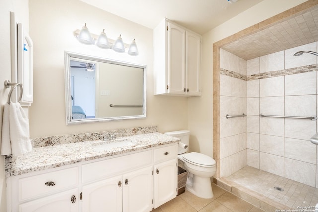 bathroom with a tile shower, vanity, tile patterned floors, and toilet