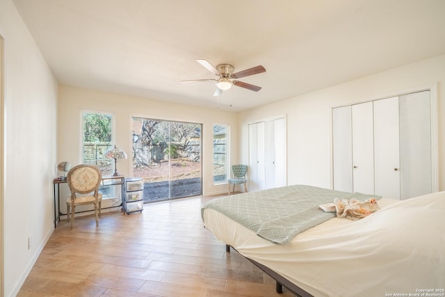 bedroom with ceiling fan, hardwood / wood-style flooring, access to outside, and multiple closets