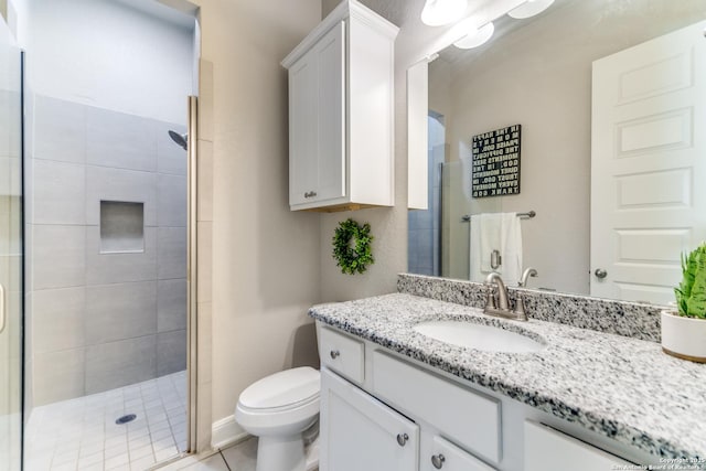 bathroom featuring tile patterned floors, vanity, toilet, and a shower with shower door