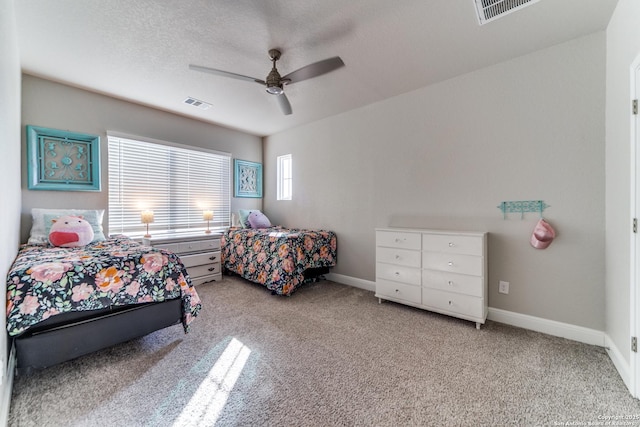 carpeted bedroom with ceiling fan and a textured ceiling