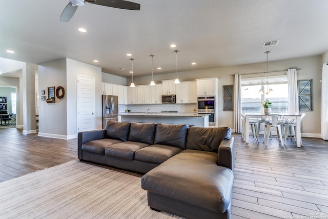 living room featuring a textured ceiling, light hardwood / wood-style flooring, and ceiling fan