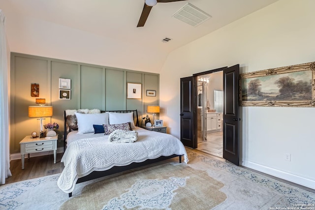 bedroom with hardwood / wood-style flooring, ensuite bathroom, lofted ceiling, and ceiling fan