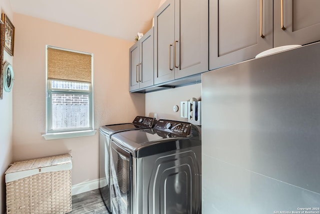 clothes washing area with cabinets, washer and clothes dryer, and hardwood / wood-style floors