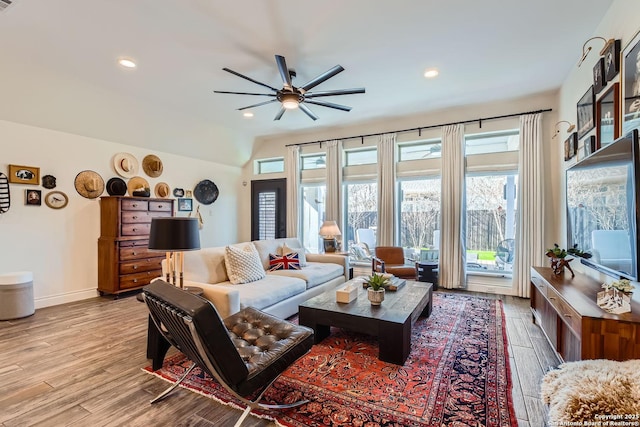 living room with ceiling fan, lofted ceiling, and light wood-type flooring