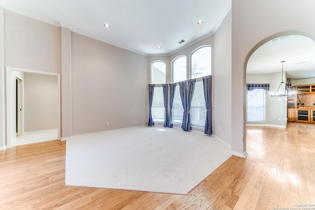 empty room featuring crown molding, light hardwood / wood-style floors, and a towering ceiling