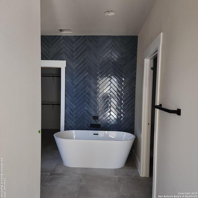 bathroom with tile patterned floors, a tub to relax in, and tile walls