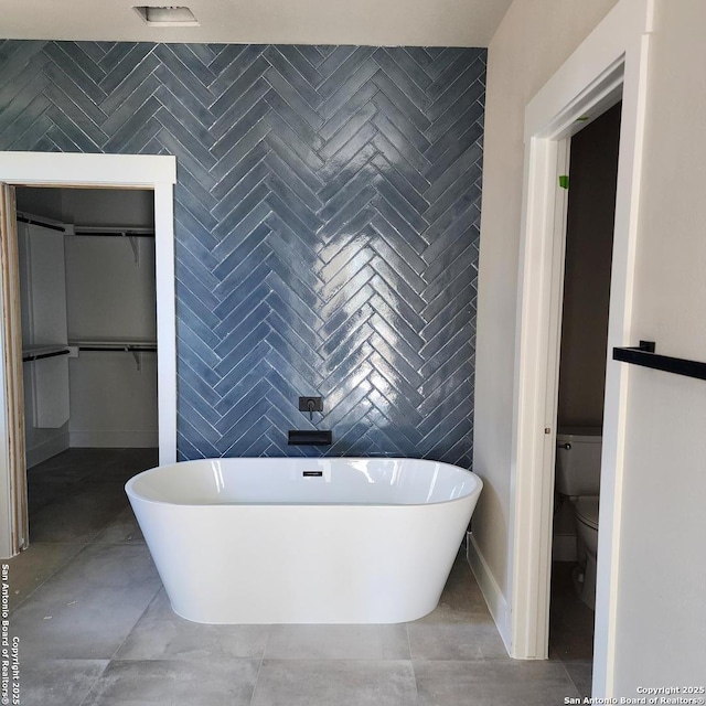 bathroom with tile walls, a tub, and toilet