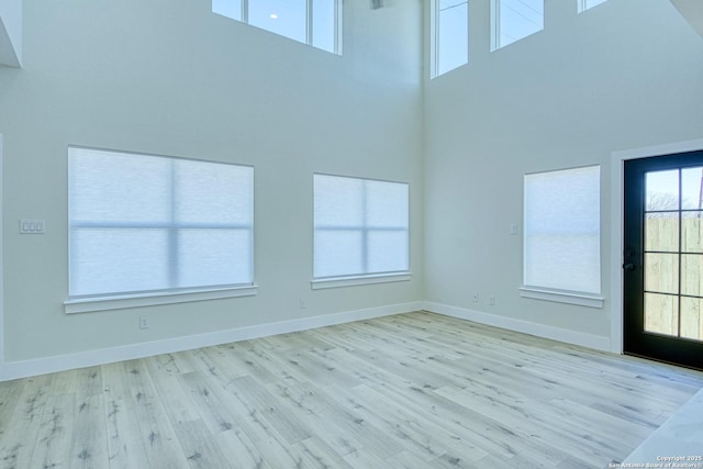 unfurnished living room with a towering ceiling and light hardwood / wood-style flooring